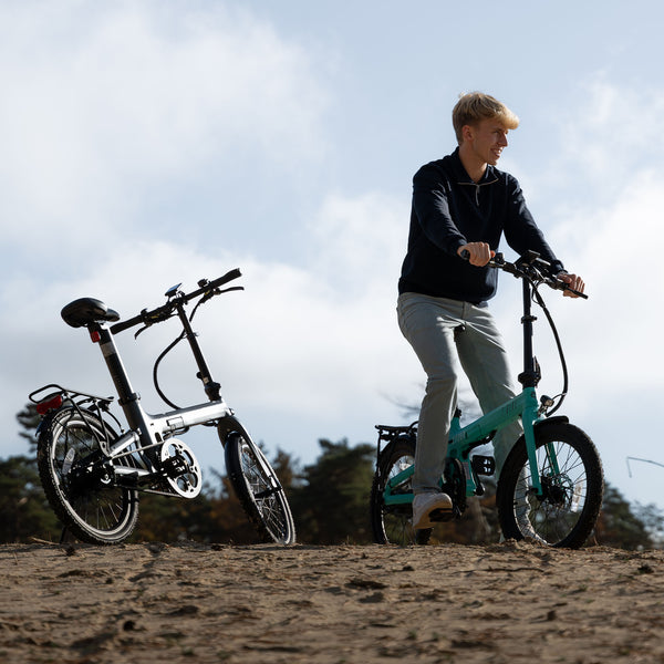 Image of a man riding the turquoise Carbon Fibre 250 bike on a beach